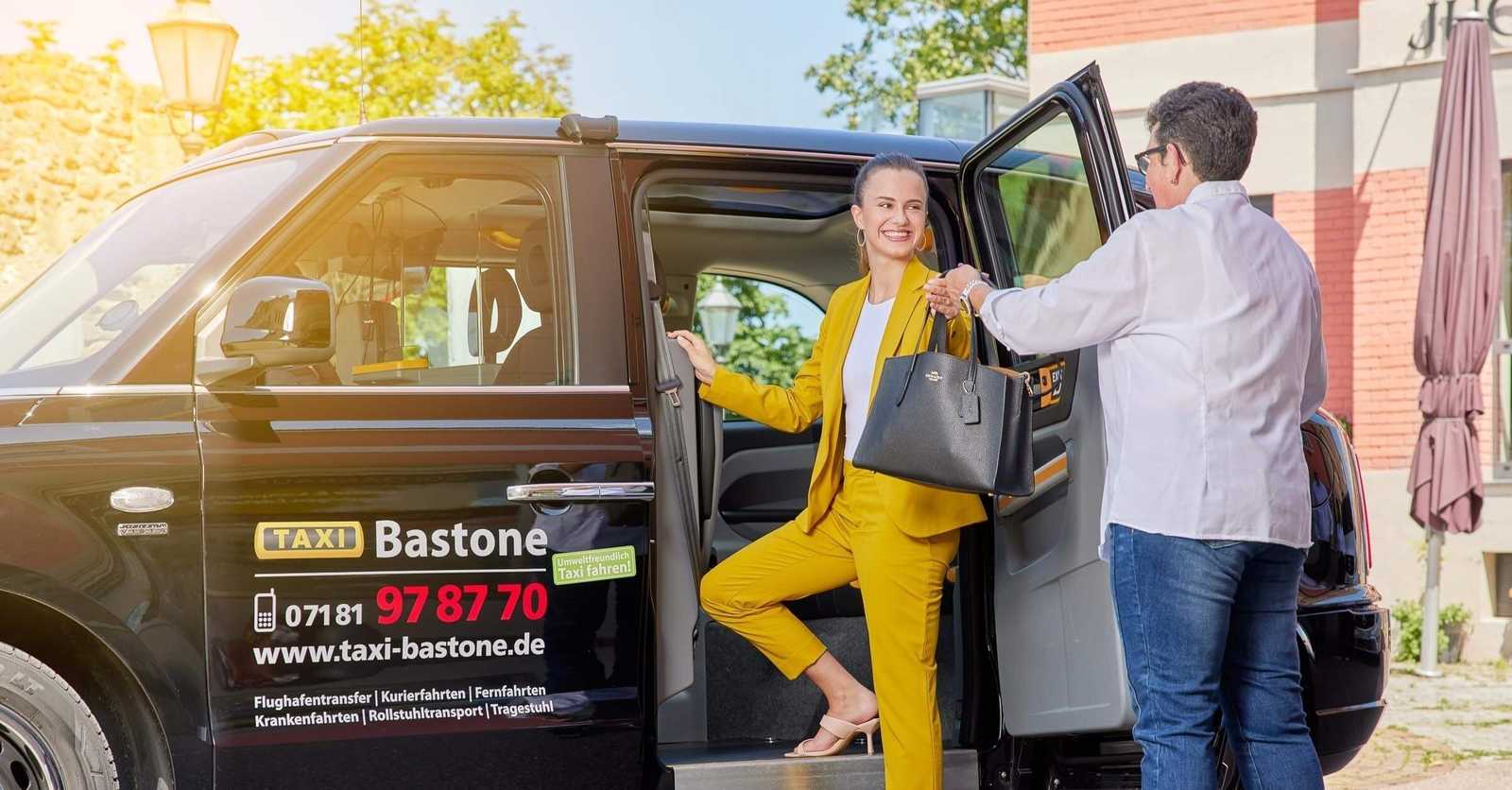 Fahrer hält einem Fahrgast die Tür des Taxis auf